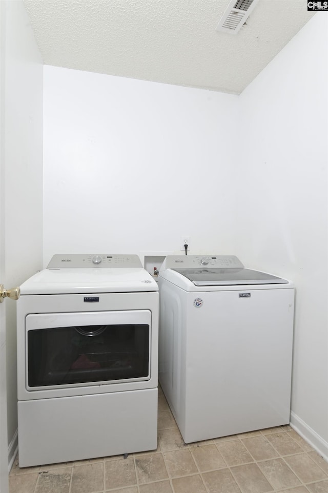 washroom featuring washing machine and clothes dryer and a textured ceiling