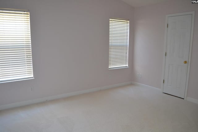 unfurnished bedroom featuring light colored carpet and multiple windows