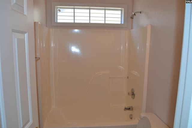 bathroom featuring shower / bathing tub combination, a healthy amount of sunlight, and toilet