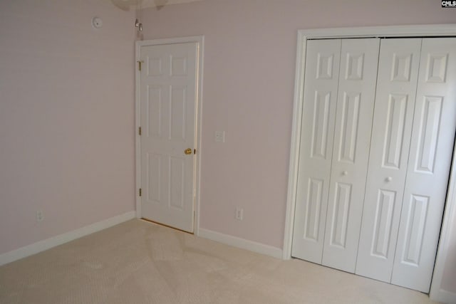 unfurnished bedroom with a closet and light colored carpet