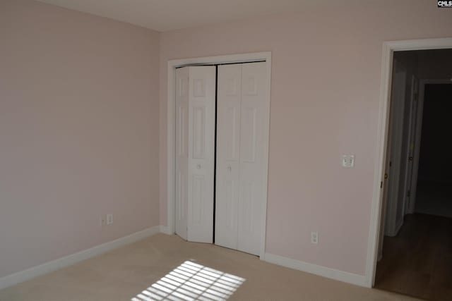 unfurnished bedroom featuring a closet and light colored carpet