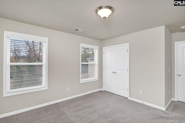 unfurnished bedroom with a closet, light colored carpet, and multiple windows