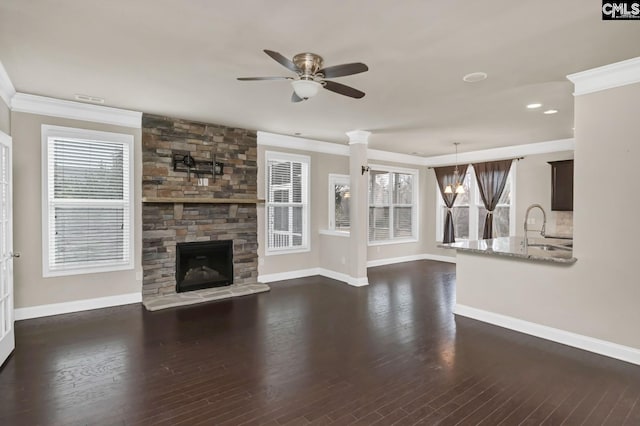 unfurnished living room featuring dark hardwood / wood-style flooring, ceiling fan, crown molding, sink, and a fireplace