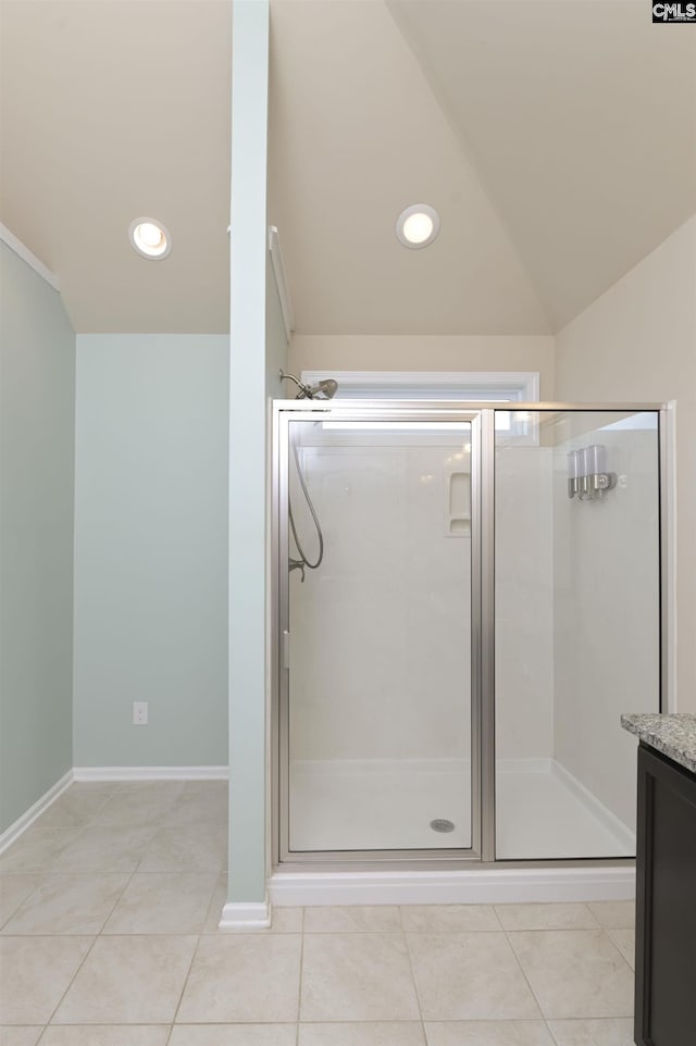 bathroom with tile patterned floors, vanity, walk in shower, and vaulted ceiling