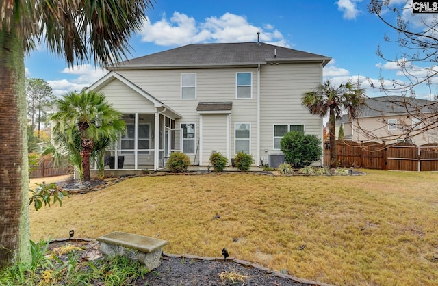 rear view of house featuring a yard and a sunroom