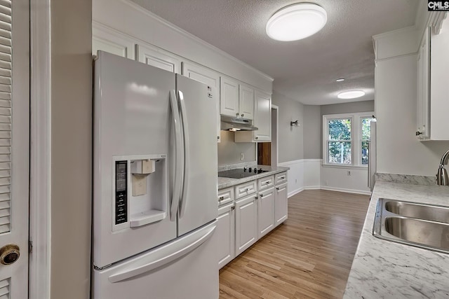 kitchen featuring sink, white refrigerator with ice dispenser, black electric cooktop, white cabinets, and light wood-type flooring