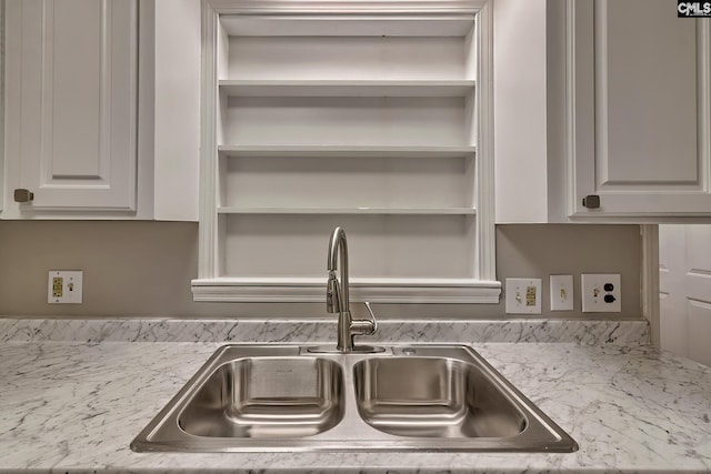 room details featuring white cabinetry, light stone countertops, and sink