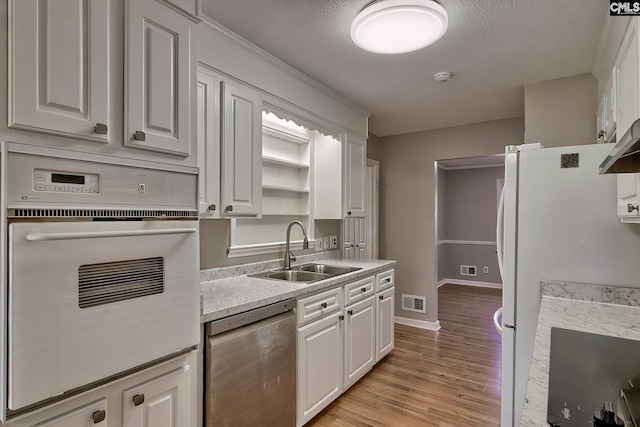 kitchen featuring a textured ceiling, white cabinetry, sink, and white appliances