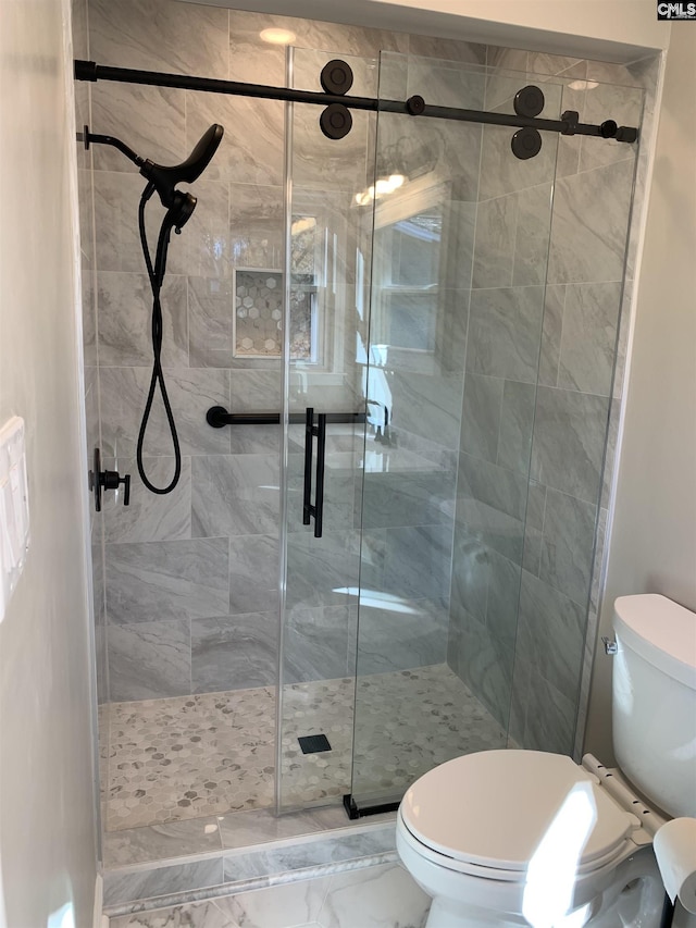 bathroom with a shower with door and toilet