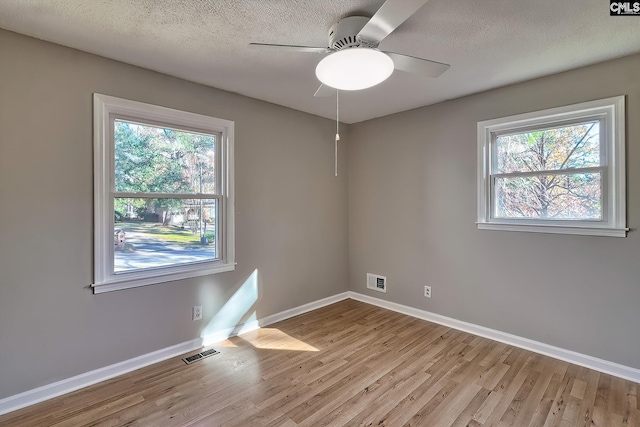 empty room with ceiling fan, light wood-type flooring, and a wealth of natural light