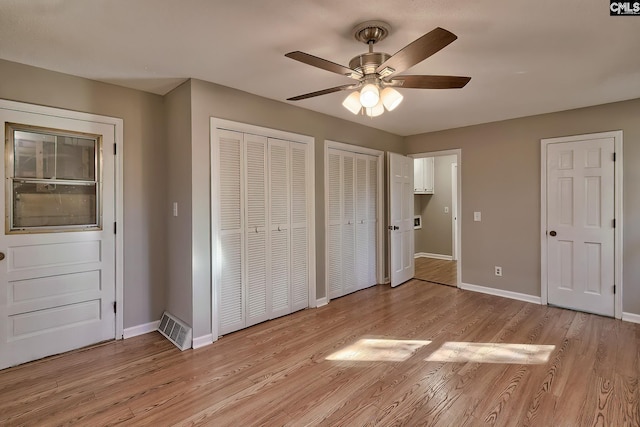 unfurnished bedroom with multiple closets, ceiling fan, and light hardwood / wood-style floors