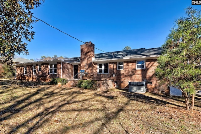 back of house with central AC and a yard