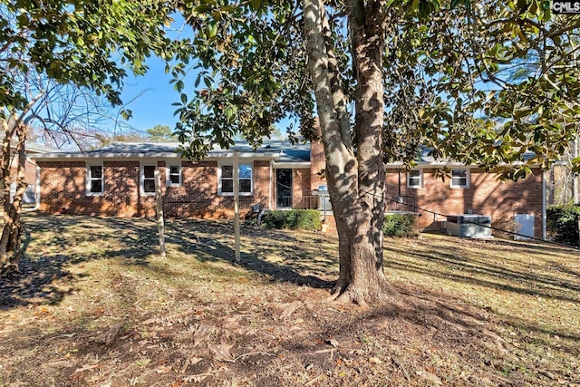 rear view of house with cooling unit and a yard