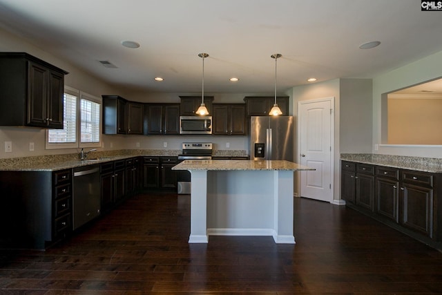 kitchen featuring dark brown cabinetry, stainless steel appliances, dark hardwood / wood-style flooring, decorative light fixtures, and a kitchen island