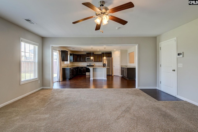 unfurnished living room featuring dark carpet and ceiling fan