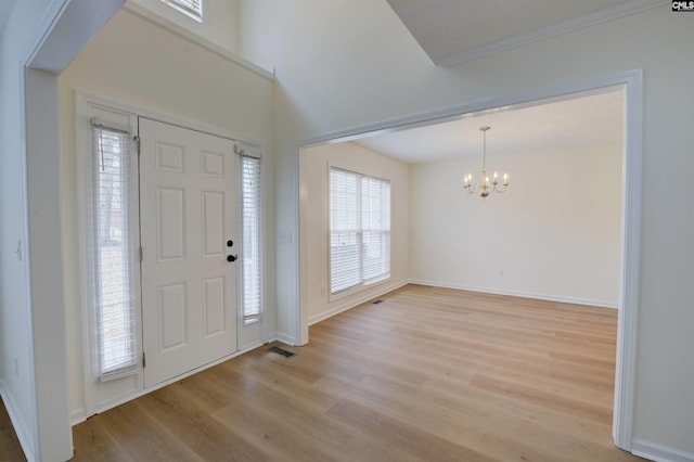 foyer entrance featuring a notable chandelier, light hardwood / wood-style floors, and crown molding