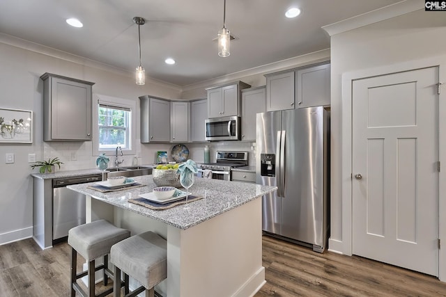 kitchen with a kitchen island, light stone counters, sink, and appliances with stainless steel finishes