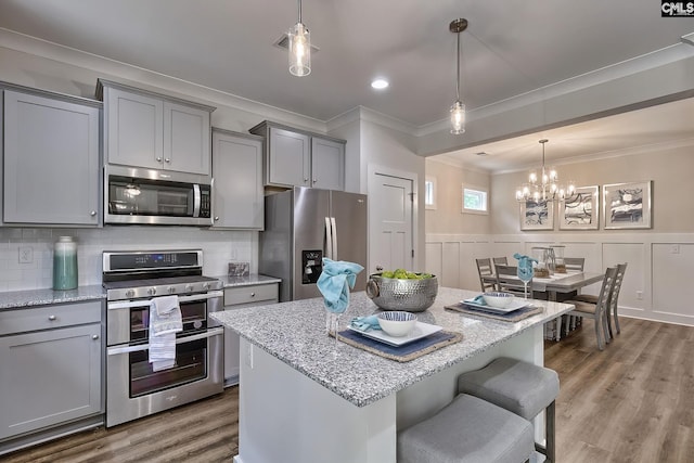 kitchen featuring pendant lighting, a center island, stainless steel appliances, and light stone counters