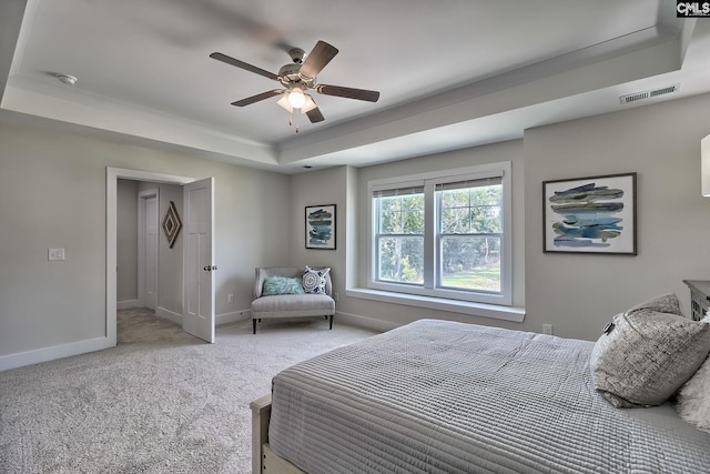 bedroom featuring light colored carpet, a raised ceiling, and ceiling fan