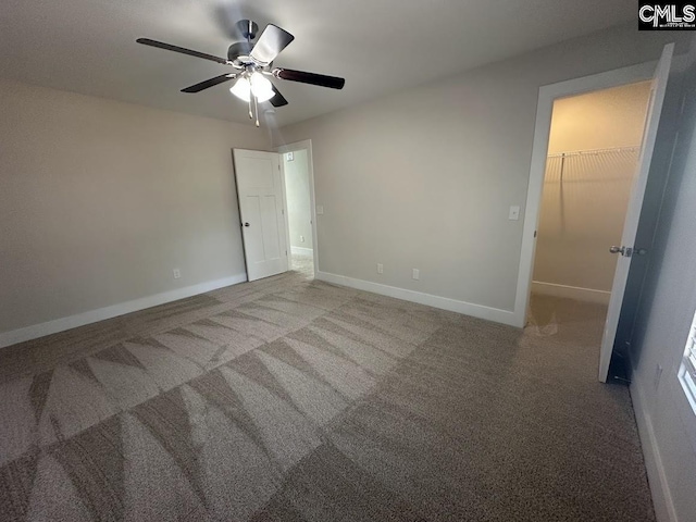 unfurnished bedroom with carpet, a spacious closet, a closet, and ceiling fan