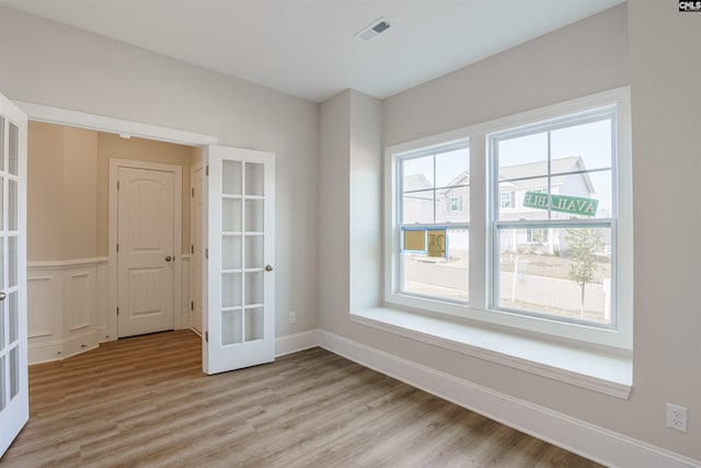 unfurnished room featuring french doors and light hardwood / wood-style flooring