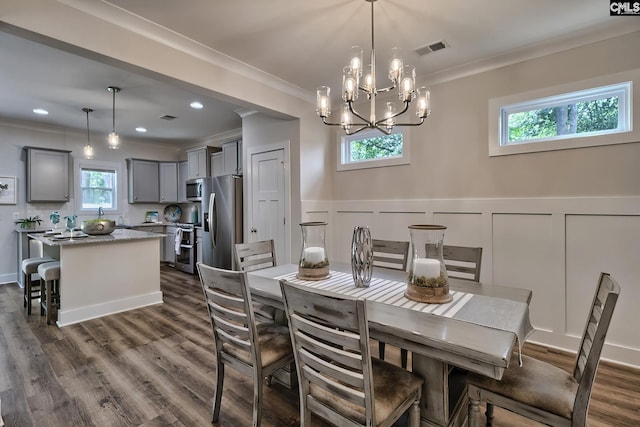 dining room featuring plenty of natural light, dark hardwood / wood-style floors, crown molding, and a chandelier