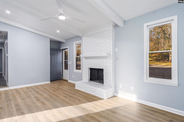 unfurnished living room with a fireplace, ceiling fan, hardwood / wood-style floors, and beamed ceiling