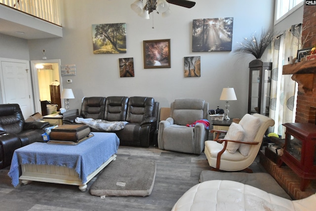 living room with ceiling fan, a towering ceiling, and dark wood-type flooring