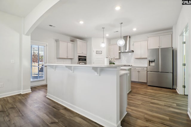 kitchen featuring white cabinets, stainless steel appliances, a center island with sink, and wall chimney exhaust hood