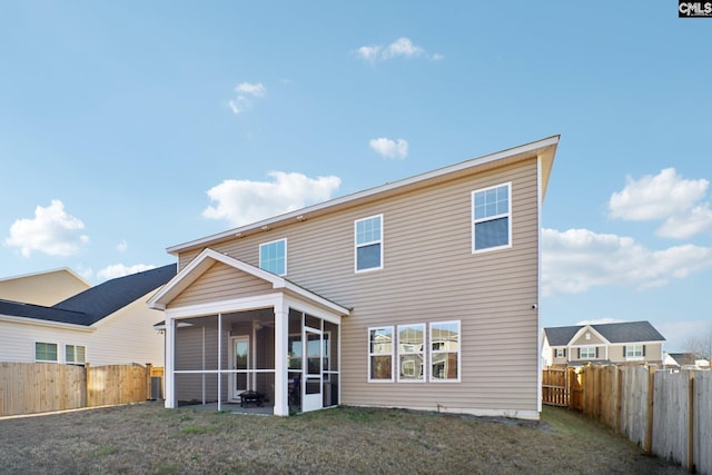 back of house featuring a lawn and a sunroom