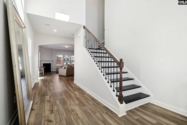 stairway featuring a towering ceiling and hardwood / wood-style flooring