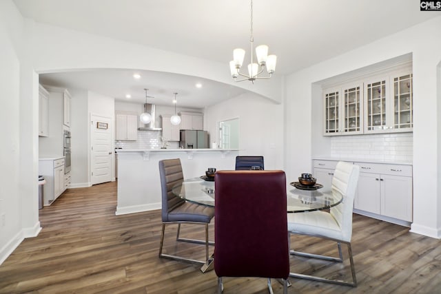 dining area with dark hardwood / wood-style flooring and an inviting chandelier