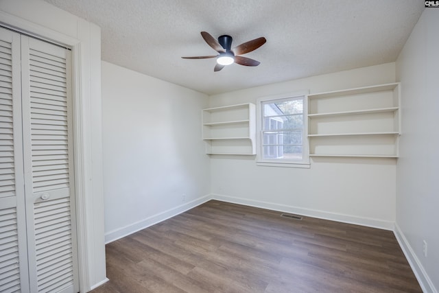 unfurnished bedroom featuring ceiling fan, a closet, dark wood-type flooring, and a textured ceiling