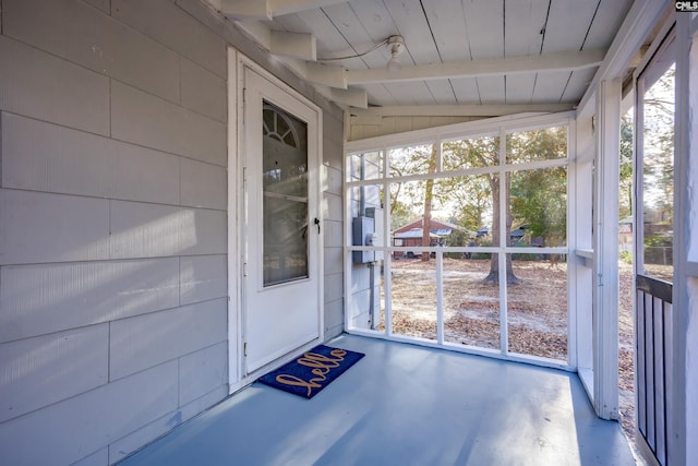 unfurnished sunroom featuring vaulted ceiling with beams, wood ceiling, and a wealth of natural light