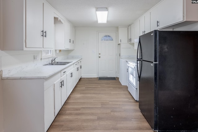 kitchen with white cabinets, black refrigerator, sink, light wood-type flooring, and white range oven