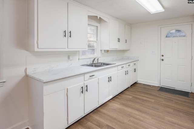 kitchen featuring a textured ceiling, light wood-type flooring, white cabinetry, and sink