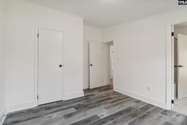 unfurnished bedroom with ornamental molding, a closet, and dark wood-type flooring