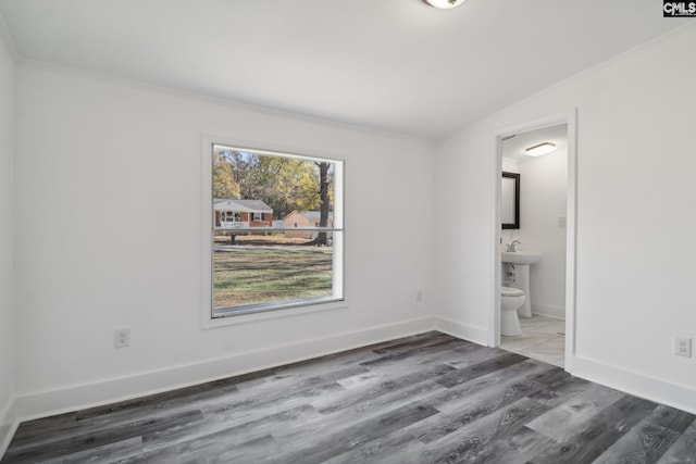 spare room featuring hardwood / wood-style floors, ornamental molding, and lofted ceiling