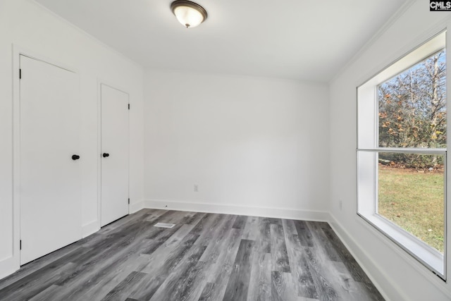 spare room with ornamental molding and dark wood-type flooring