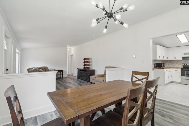 dining area with hardwood / wood-style floors, vaulted ceiling, and an inviting chandelier