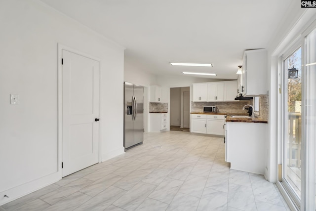 kitchen featuring appliances with stainless steel finishes, tasteful backsplash, vaulted ceiling, sink, and white cabinets