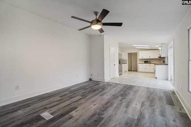 unfurnished living room with ceiling fan, sink, and light hardwood / wood-style floors