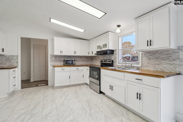 kitchen with wood counters, lofted ceiling, appliances with stainless steel finishes, tasteful backsplash, and white cabinetry