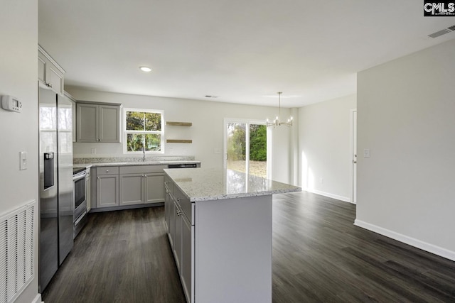 kitchen featuring dark hardwood / wood-style flooring, light stone counters, gray cabinetry, decorative light fixtures, and a center island