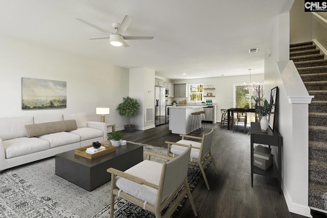 living room featuring ceiling fan with notable chandelier and dark hardwood / wood-style floors