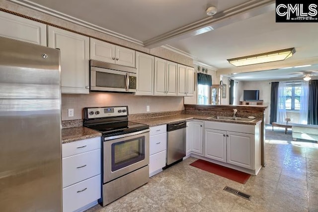 kitchen featuring kitchen peninsula, ornamental molding, stainless steel appliances, sink, and white cabinetry