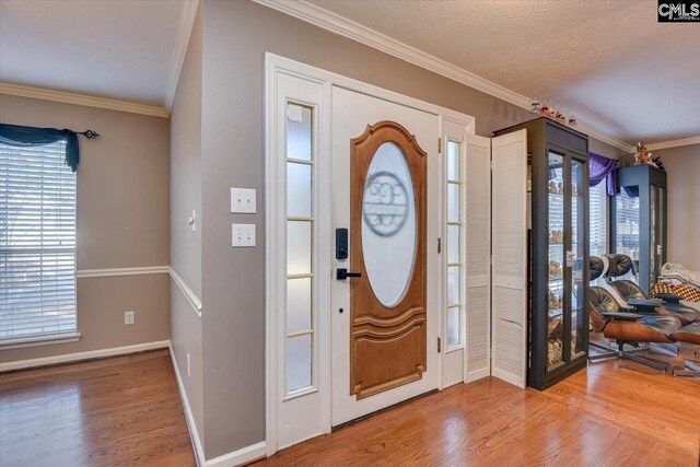 entrance foyer with wood-type flooring, crown molding, and a wealth of natural light