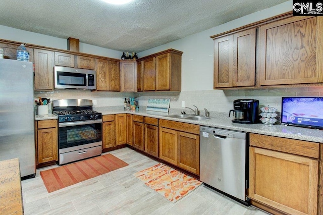 kitchen featuring appliances with stainless steel finishes, a textured ceiling, tasteful backsplash, and sink