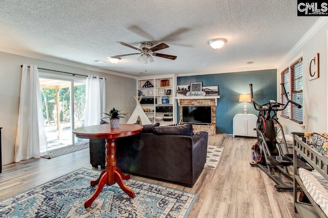 living room featuring light hardwood / wood-style floors, crown molding, a textured ceiling, and a brick fireplace