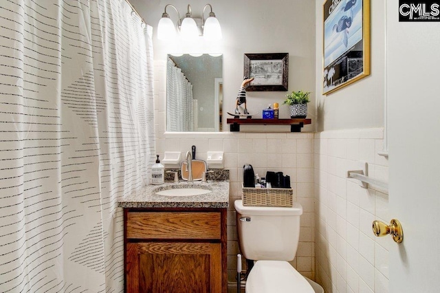 bathroom with vanity, tile walls, and toilet